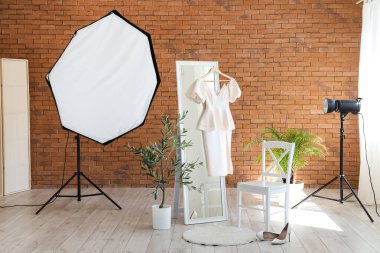 Profesyonel ekipman, sandalye, ayna ve elbise ile şık bir fotoğraf stüdyosu.