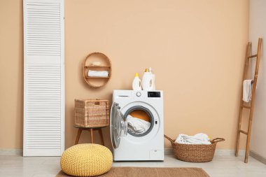 Modern çamaşır makinesi, sepet ve deterjanı olan çamaşır odası.