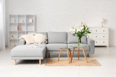 Gri kanepe ve sehpanın üzerinde nilüfer çiçekleri olan şık bir oturma odası.