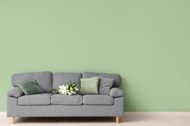 Gri kanepede, şık oturma odasında bir buket nilüfer çiçeği.