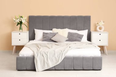 Yatak odasının içinde rahat yatağın yanındaki komodinlerin yanında nilüfer çiçekleri var.