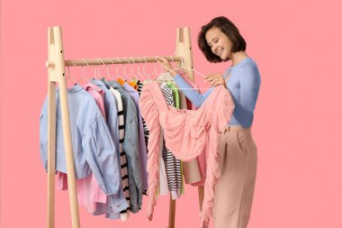 Pembe arka planda farklı giysileri olan güzel bir kadın.