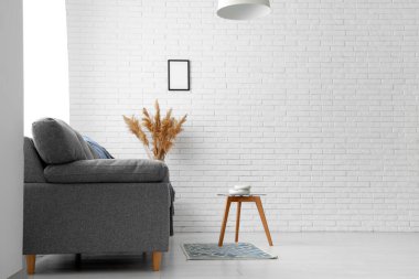 Oturma odasının iç tarafında büyük siyah bir kanepe ve kahve masası.