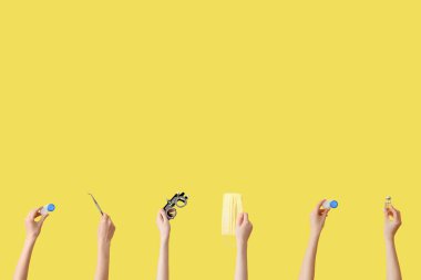 Sarı zemin üzerinde lensler, termometre, tıbbi maske ve deneme optik çerçeve ile eller