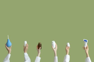 Kadın eli lavman, haplar ve yeşil arka planda termometre.