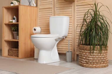 Seramik klozet, raf ünitesi ve bitkilerle dolu modern tuvalet.