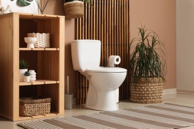 Tuvalet klozeti ve raf ünitesi olan temiz, modern bir tuvalet.