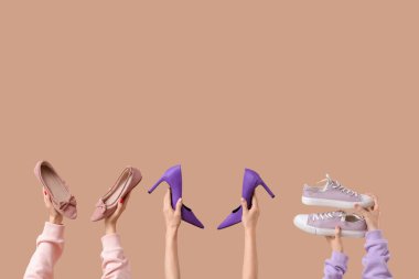 Bej arka planda topuklu ve spor ayakkabılı bir kadın.