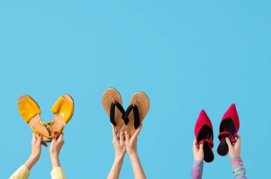 Mavi arka planda terlikleri ve topukları olan kadın elleri.