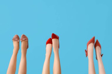 Mavi arka planda farklı topuklu kadın bacakları.