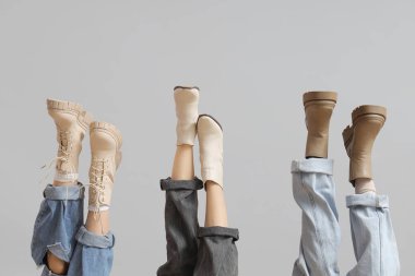 Gri arka planda farklı çizmeleri olan kadın bacaklar.