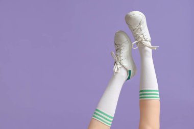 Leylak arka planda spor ayakkabılı kadın bacakları.