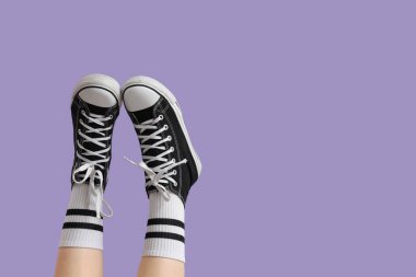 Leylak arka planda spor ayakkabılı kadın bacakları.