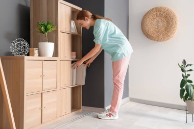 Genç bir tıp öğrencisi evdeki raflardan klasör alıyor.