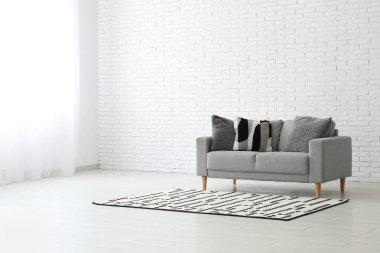 Oturma odasının içinde yastıklar ve halı olan rahat bir kanepe.