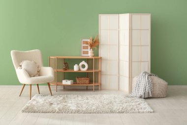 Koltuk, raf ünitesi, katlanan perde ve pofuduk halı oturma odasında.