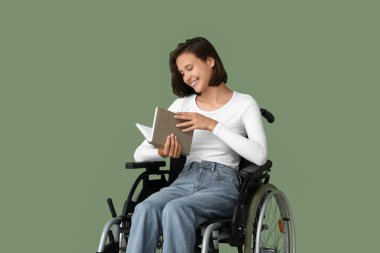 Tekerlekli sandalyedeki genç güzel kadın yeşil arka plan kitabı okuyor.
