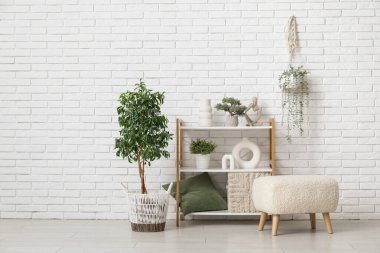 Raflar, puf ve çiçek, beyaz tuğla duvarın yanında.