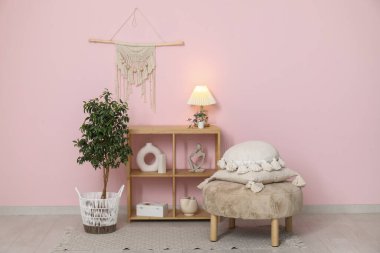 Rafa kaldırma ünitesi, yastıklı puf ve beyaz tuğla duvarın yanındaki ev bitkisi.