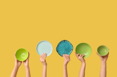 Sarı arkaplanda boş tabakları tutan eller