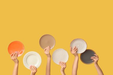 Sarı arkaplanda boş tabakları tutan eller