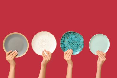 Kırmızı arkaplanda boş tabakları tutan eller