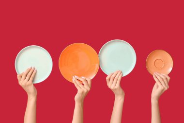 Kırmızı arkaplanda boş tabakları tutan eller