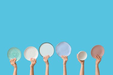 Mavi arkaplanda boş tabakları tutan eller