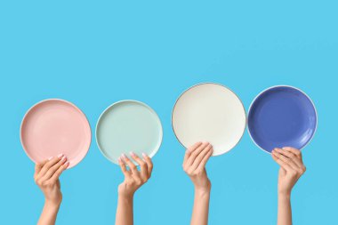 Mavi arkaplanda boş tabakları tutan eller