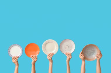 Mavi arkaplanda boş tabakları tutan eller