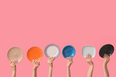 Pembe arka planda boş tabakları tutan eller