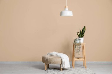 Kahve masası, puf, ekose ve asılı lambalı şık bir oturma odası.