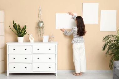 Evdeki bej duvara boş tuval asan genç bir kadın. Arka plan