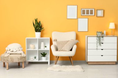 Koltuk, çekmeceler, raf ünitesi ve oturma odasında yastıklı puf.