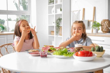 Sevimli küçük kızlar mutfakta tatlı tost yiyorlar.