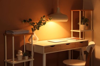 Modern dizüstü bilgisayarı ve parlak lambası olan şık bir iş yeri.