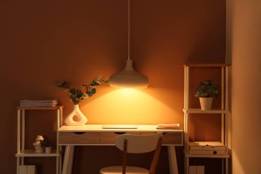 Modern dizüstü bilgisayarı ve parlak lambası olan şık bir iş yeri.