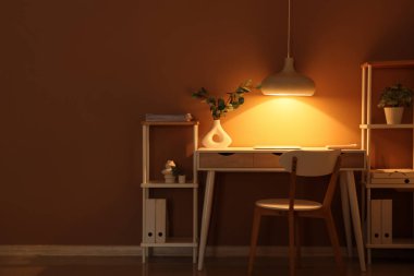 Modern dizüstü bilgisayarı ve parlak lambası olan şık bir iş yeri.