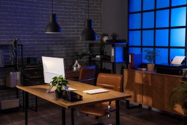 Çalışma yeri, raf üniteleri ve parlayan lambaları olan karanlık ofisin içinde.