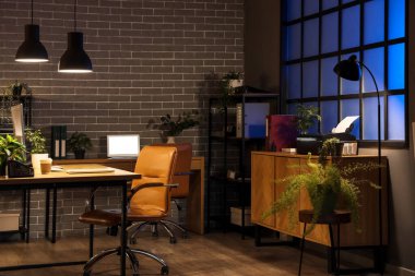 Masaları, çekmeceleri ve parlayan lambaları olan karanlık ofisin içinde.