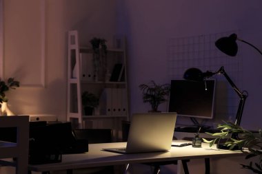 Masasında parlak lamba olan bir dizüstü bilgisayar.