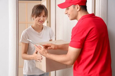 Genç bir kadın teslimatçıdan paket alıyor.