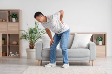 Evde sırt ağrısı çeken genç bir adam.