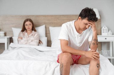 Yatak odasında oturan üzgün genç adam. Cinsel sorunlar kavramı