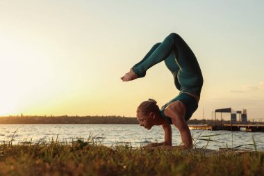Nehir kenarında yoga yapan bir kadın silueti.
