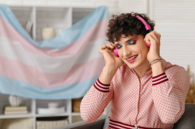 Evde müzik dinleyen kulaklıklı genç bir transseksüel kadın.