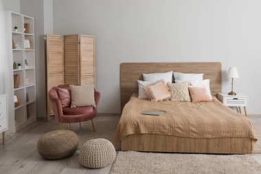 Rahat yatağı, rahat koltuğu ve raf ünitesi olan modern bir yatak odası.