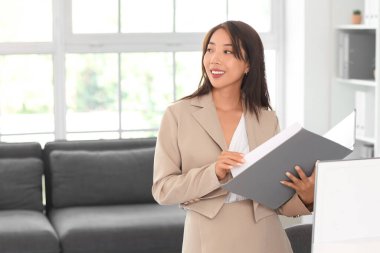 Ofisinde klasörü olan Asyalı iş kadını.