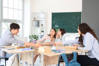 Sınıftaki sıralarda okuyan bir grup genç öğrenci.