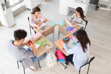 Sınıftaki sıralarda okuyan bir grup genç öğrenci.